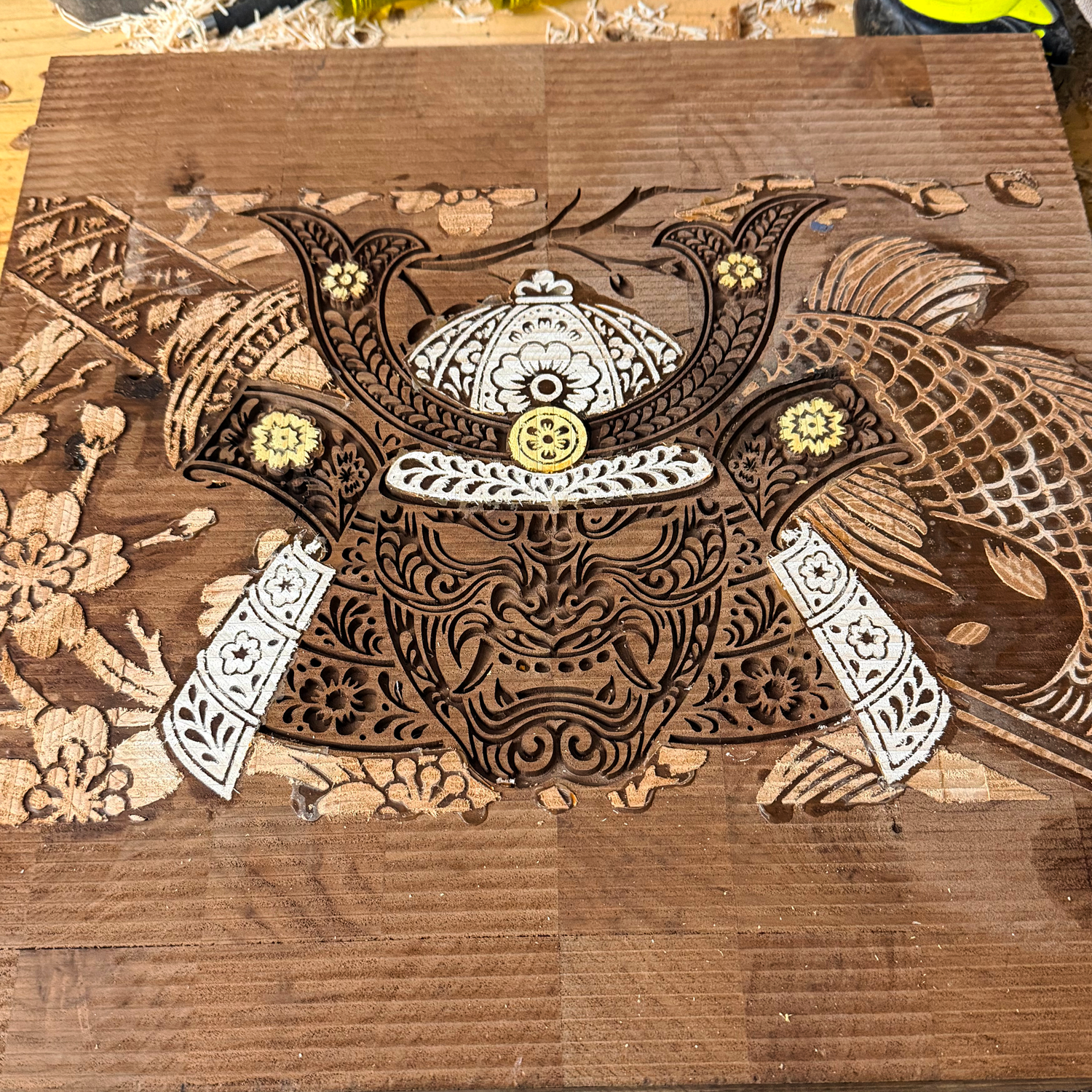 In-progress walnut end-grain cutting board featuring a complex CNC inlay of a samurai, koi fish, and rose blossoms crafted from yellowheart, maple wood, and cherry woodwork.