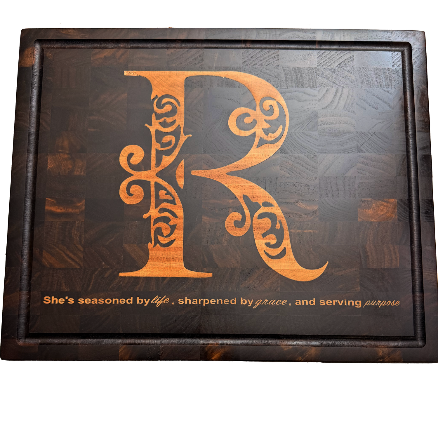 Personalized chopping board made from dark end-grain walnut featuring an intricate Japanese maple leaf and custom monogram 'R' inlay with a personalized phrase, showcasing precision CNC craftsmanship.